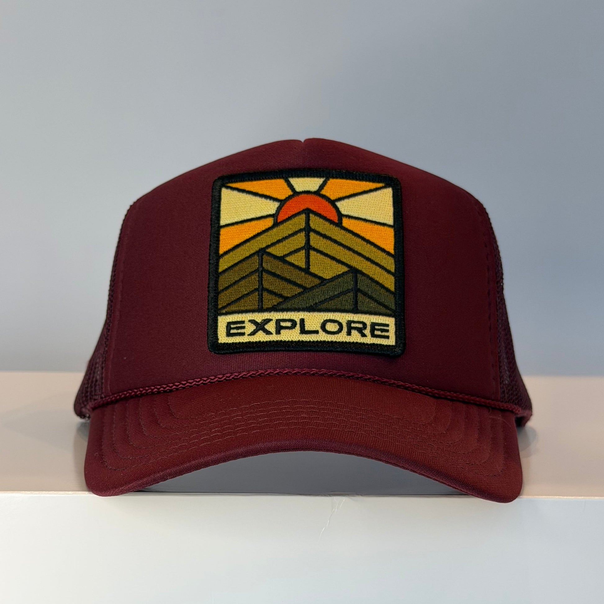 Port Sandz Burgundy trucker hat with "EXPLORE" embroidered patch on the front panel. 