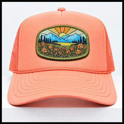 Port Sandz peach colored California Poppy Mesh-Back Trucker Hat. Vicose embroidered patch on front picturing sun and rays, mountains and California's State Flower, the golden poppy in fields. 