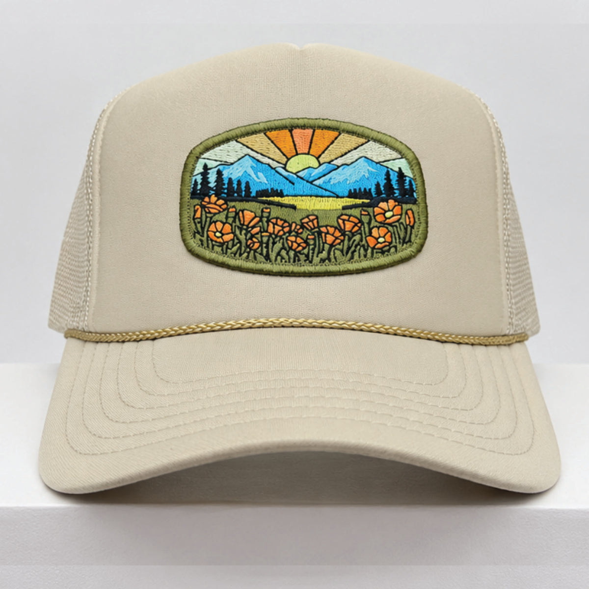Port Sandz tan colored California Poppy Mesh-Back Trucker Hat. Vicose embroidered patch on front picturing sun and rays, mountains and California's State Flower, the golden poppy in fields. 